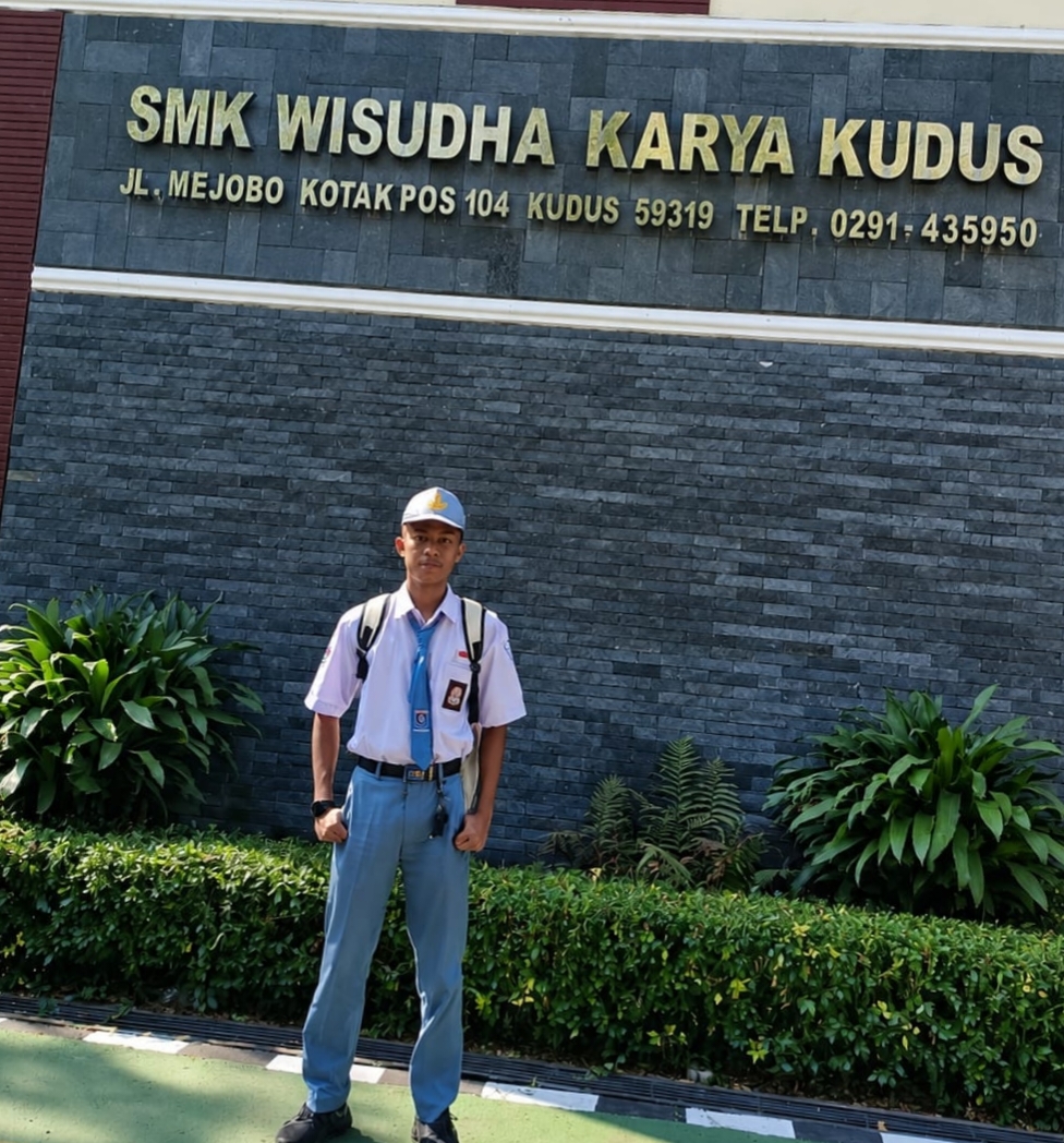 Reza dengan bangga foto di depan sekolahnya di Kudus